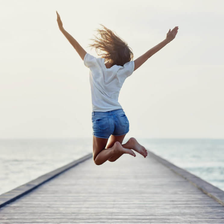 Back view of jumping girl on the pier biofar alimentation spéciale été